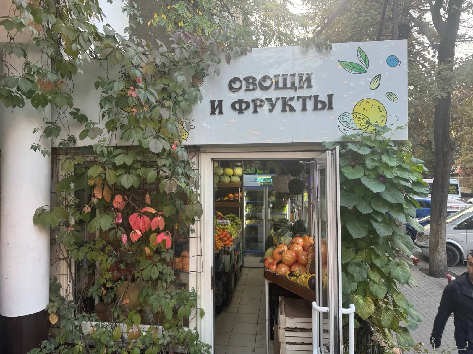Вход в магазин «Овощи и фрукты» под вывеской с лимоном, дверь открыта